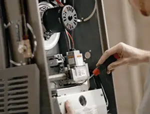 Furnace repair technician inspecting internal components and wiring in Fort Wayne, IN