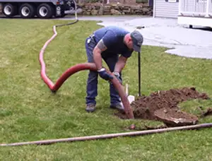 Septic pumping technician servicing a residential septic tank with a vacuum hose in Fort Wayne, IN