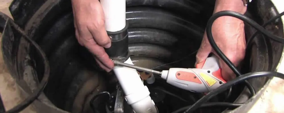 Sump pump installation technician connecting PVC discharge piping in Fort Wayne, IN